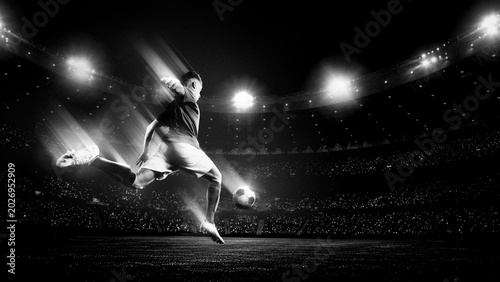 Soccer player jumping for powerful kick in black and white stadium light. Concept of decisive attack, dramatic match moment, sport campaign and cinematic football energy.
