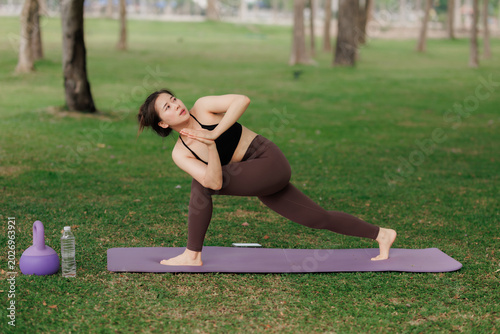 Fit girl doing yoga meditation in the public garden.