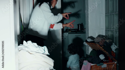 Quadro su tela Mother standing in hallway playfully creating hand shadows on wall to amuse todd