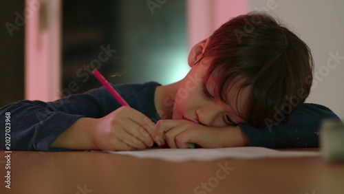 Obraz na płótnie Young boy pausing during homework with pencil in hand staring at worksheet in pe