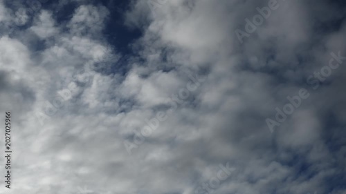 Time lapse of white and gray summer clouds moving across a dark blue sky. The clouds fill the frame.
