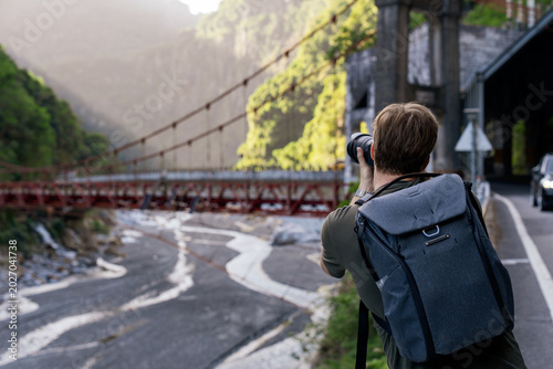 Fotografi Tourist photographing bridge and valley scenery