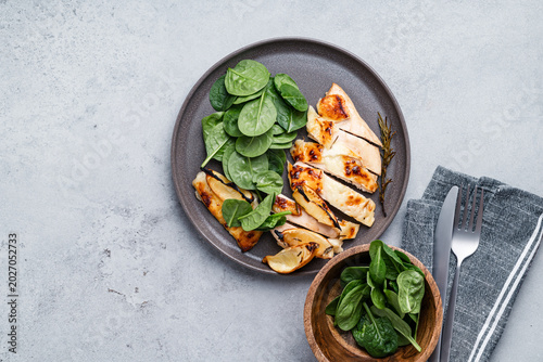 Roasted chicken breast with lemon and halloumi  served with fresh baby spinach leaves, top view