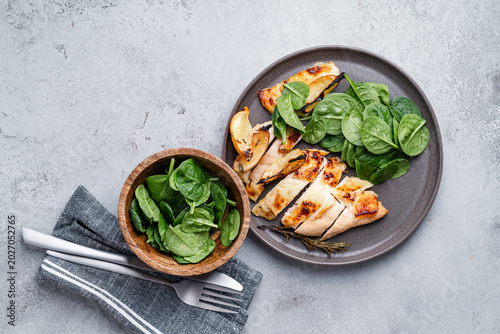 Roasted chicken breast with lemon and halloumi  served with fresh baby spinach leaves, top view