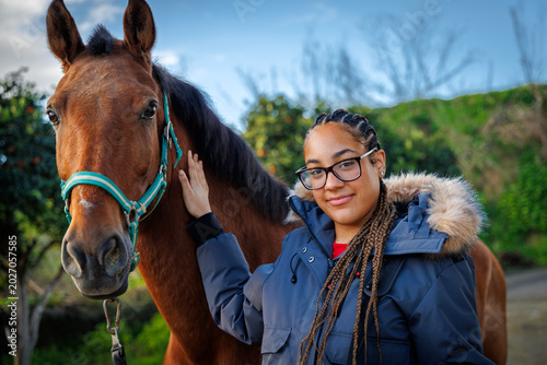 Fotografie Smiling Young Girl Standing with Horse Outdoors