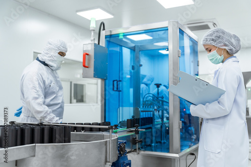 Foto Clean room workers examine medical production machinery wit