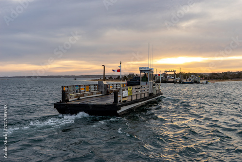 View of the Chappy Ferry in Martha's Vineyard with a person in the booth crossing the water towards the dock at sunset Edgartown, Massachusetts, United States.