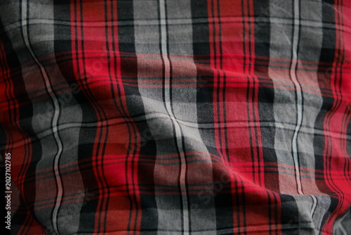 Cotton flannel fabric background with a repeating checkered pattern and a combination of red, gray, and black colors