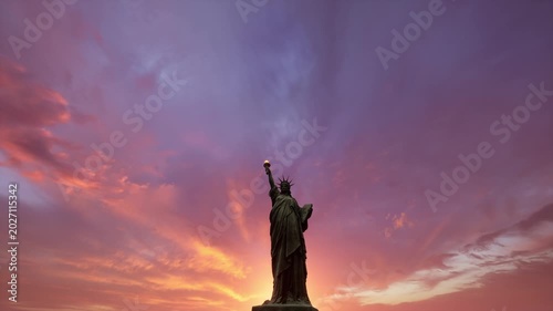 Iconic Statue of Liberty stands silhouetted against a vivid purple and pink sunset sky over New York. Perfect for patriotic, travel, tourism, and freedom themed content.