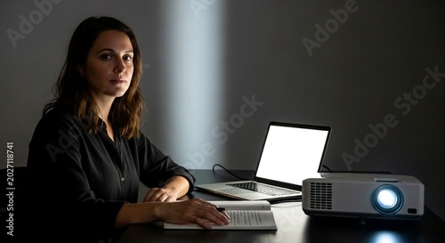 Woman using laptop with projector in dark office