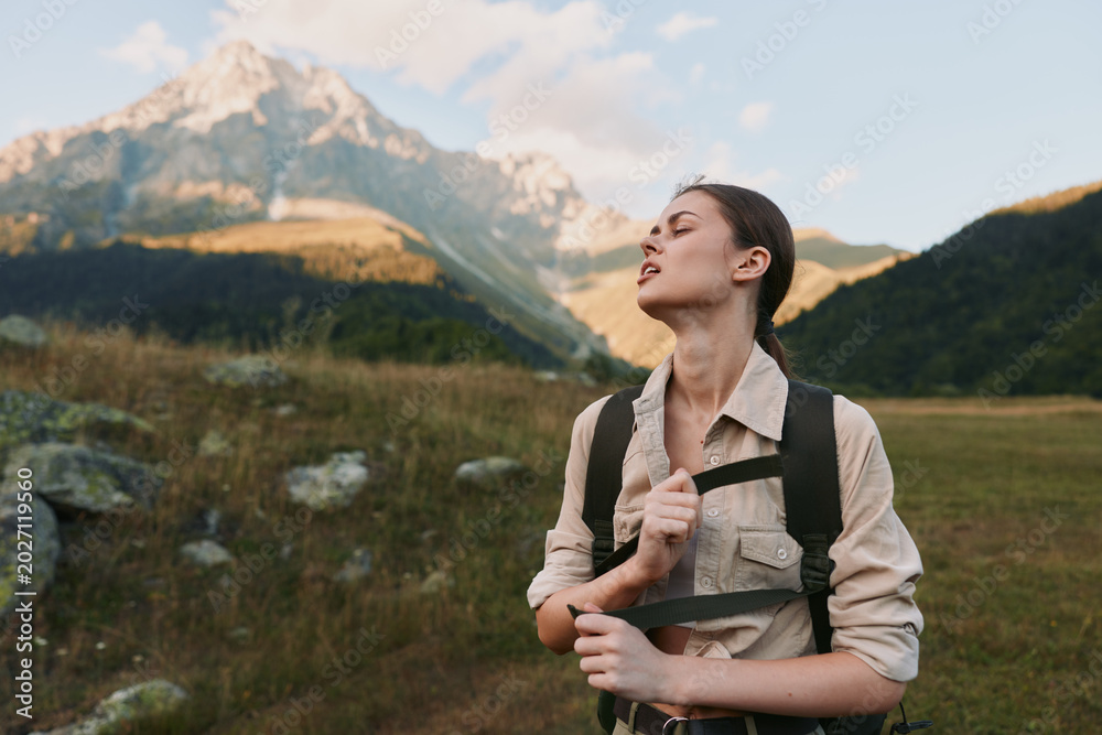 Fototapeta premium Young woman with brunette hair enjoys a peaceful moment hiking in the mountains during golden hour with a relaxed expression and casual outdoor clothing.