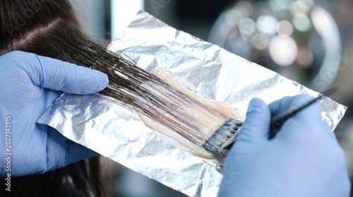 Stylist applying hair lightener for balayage on foil