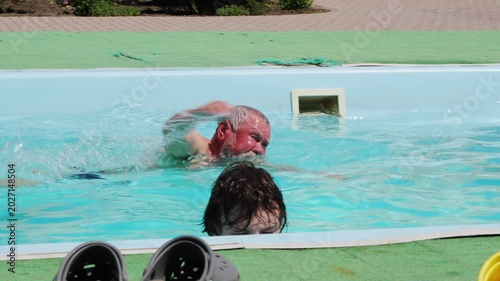Swimmer practices in pool with observer during sunny afternoon