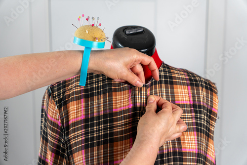 Foto Woman marking and securing fabric on tailor mannequin with sewing pins during fitting and dressmaking process