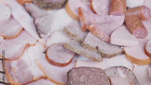 Closeup of assorted cured meats. Display of various sliced ham and salami. Studio shot showcasing assortment of seasoned meats with marble textures and soft lighting