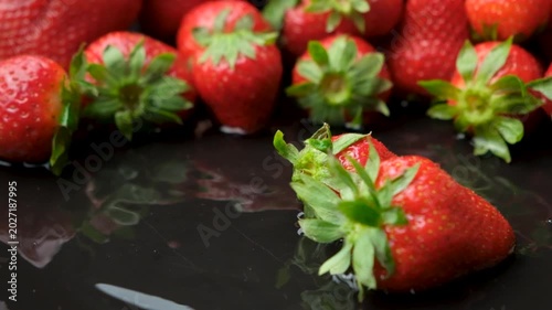 Juicy red strawberries dropping in water with big splashes macro.