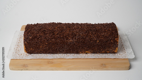 Meranti Swiss roll cake with chocolate topping served in a simple presentation. This famous Medan souvenir is well known for its soft texture, balanced sweetness, and rich chocolate layer.