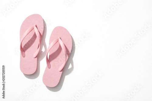 Pink flip flops arranged on pristine white backdrop top view with ample copy space