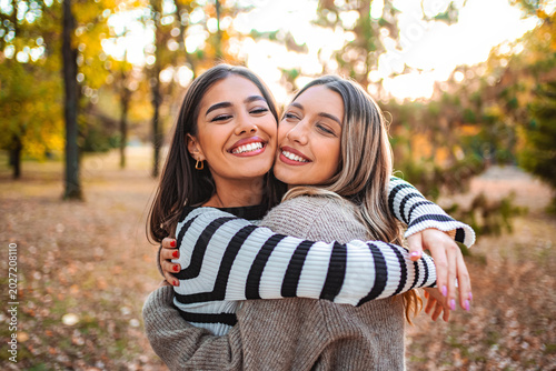 Konstfotografi Two girls share a joyful hug in an autumn park filled with colorful leaves