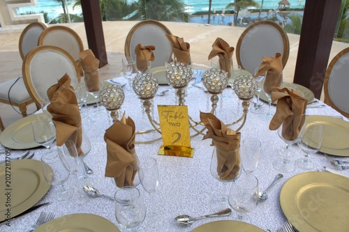 Photography Elegant oceanfront wedding reception table setting with gold accents