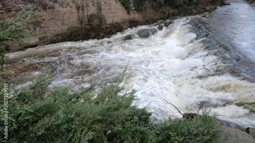 The Weiss river running between half timbered houses, Kaysersberg, Alsace, France, Europe. River with strong current flowing through the rocks.
