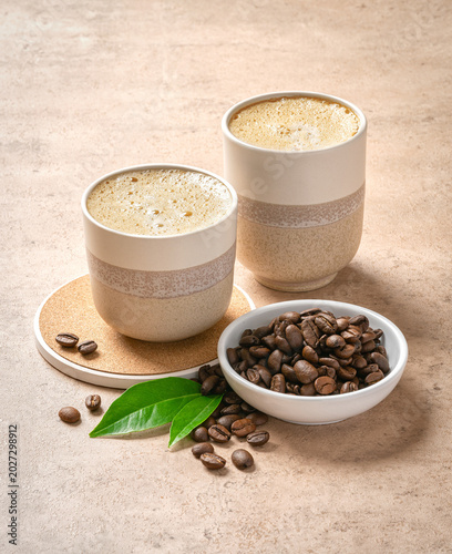 two cups of coffee on a table with coffee beans, two cups of coffee sit next to a couple of coffee beans. seamless texture
