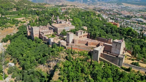 High angle view of the historic Alhambra palace complex and Alcazaba fortress in Granada. Famous UNESCO medieval Moorish architecture surrounded by scenic Andalusian mountains in Spain.
