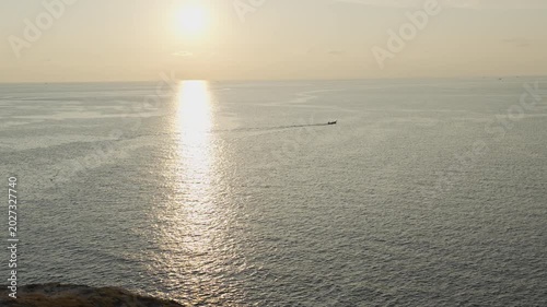 Serene Sunset Over Calm Ocean with Distant Boat Creating Peaceful and Tranquil Scene on Horizon, Water Reflecting Serene Atmosphere