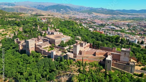 High angle view of the historic Alhambra palace complex and Alcazaba fortress in Granada. Famous UNESCO medieval Moorish architecture surrounded by scenic Andalusian mountains in Spain.