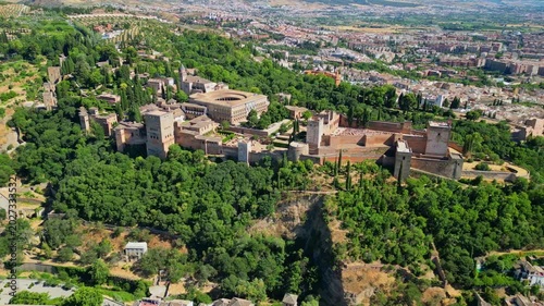 High angle view of the historic Alhambra palace complex and Alcazaba fortress in Granada. Famous UNESCO medieval Moorish architecture surrounded by scenic Andalusian mountains in Spain.