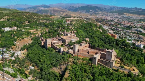 High angle view of the historic Alhambra palace complex and Alcazaba fortress in Granada. Famous UNESCO medieval Moorish architecture surrounded by scenic Andalusian mountains in Spain.