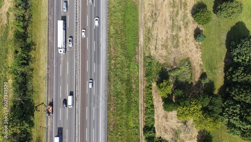 Aerial View of a Highway: A top-down perspective showcases a multi-lane highway with various vehicles, including a large semi-truck, driving through a landscape of green fields and trees.