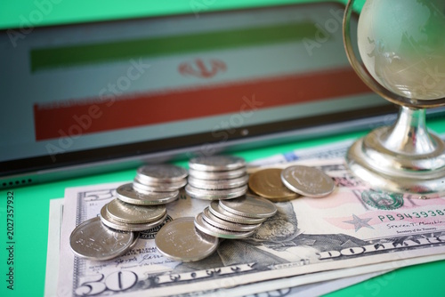 Dollar bills with coins and the Iranian flag.
