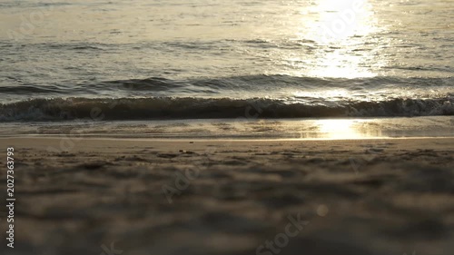 Golden Sunlight Reflects on Tranquil Beach with Gentle Waves Lapping at Shore Creating Serene and Peaceful Atmosphere