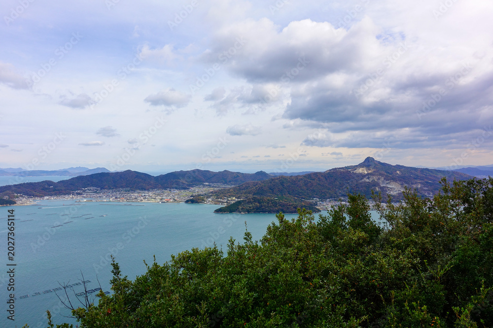 Obraz premium Panoramic coastal landscape of Seto Inland Sea and mountains beneath dramatic clouds in Shikoku Japan