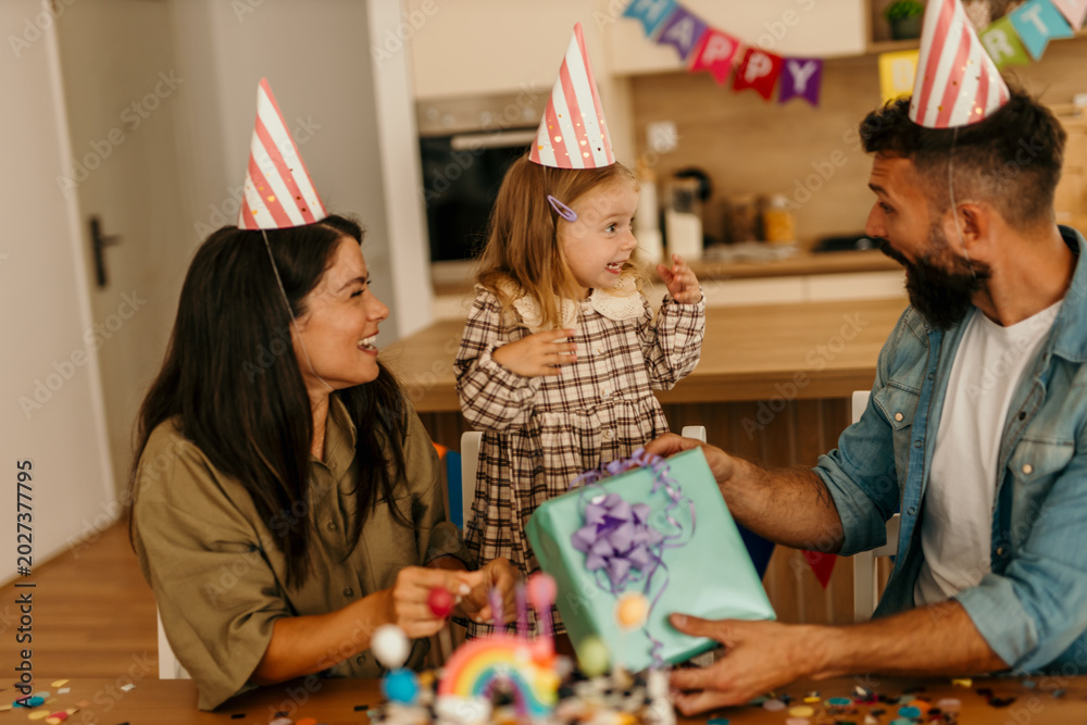 Fototapeta premium Family celebrating birthday party, opening surprise gift at home