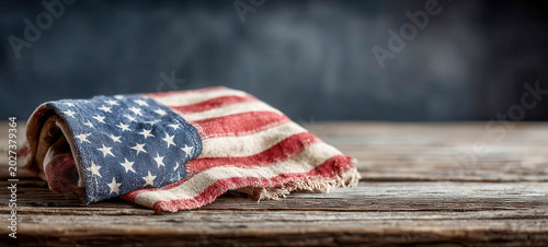 American flag folded on wooden table with dark background near Independence Day celebration