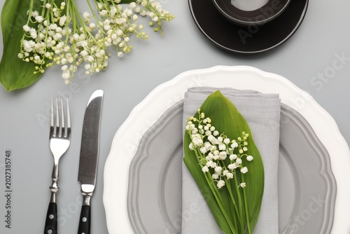 Obraz na plátně Stylish table setting with plate, cutlery, cup and lily-of-the-valley flowers on