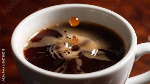 Closeup of Cream Dropping into Black Coffee Creating Ripples.
