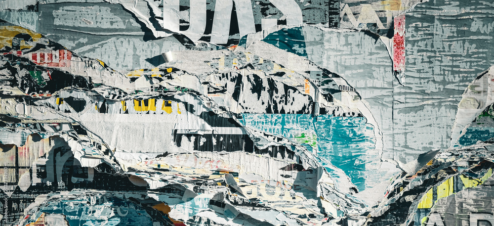 Fototapeta premium Weathered Street Poster Wall with Torn Paper Layers and Faded Urban Advertisements in Sunlight