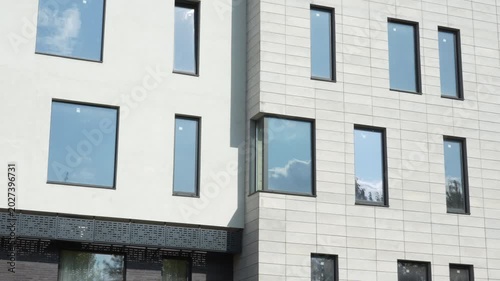 Panoramic view of elegant modern white building with large windows and minimalist architecture. Contemporary urban residential or office exterior in daylight.
