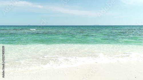 Serene Beach Scene with Clear Turquoise Water and White Sand Under Bright Blue Sky, Gentle Waves Lapping Against Sandy Shore, Ocean View