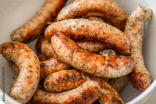 Quadro su tela Grilled sausages arranged in a white bowl showcasing a variety of textures and c