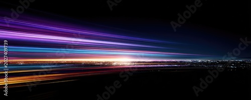 Streaking lights of purple, blue, and orange create motion blur over a dark city skyline