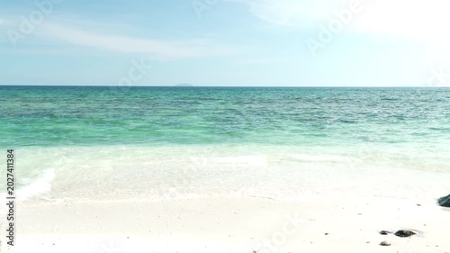 Serene Beach Scene with Clear Turquoise Ocean Water and White Sand Under Bright Blue Sky and Tranquil Horizon