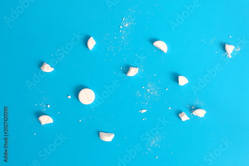On a blue background there are crushed white tablets and medicines.