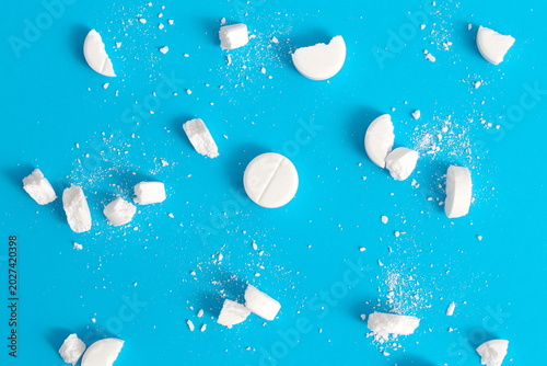 On a blue background there are crushed white tablets and medicines.