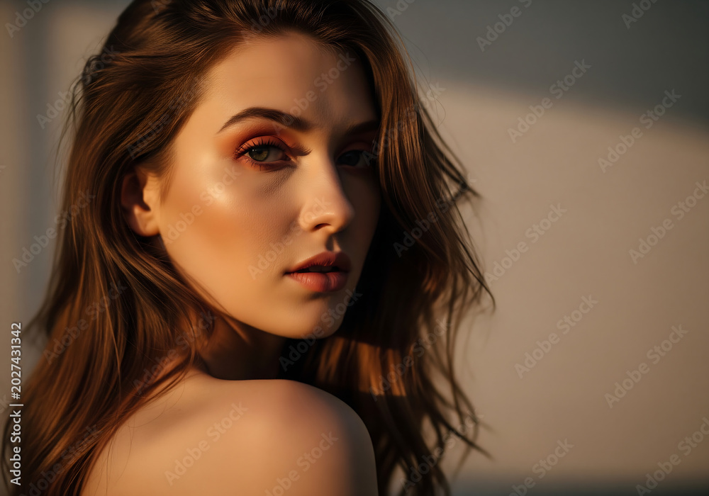 Naklejka premium Close up portrait of a woman with soft natural lighting highlighting delicate facial features and expressive eyes in a moody beauty shot