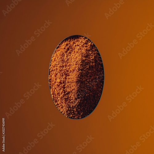 Oval pile of ground turmeric powder on a warm orange background.