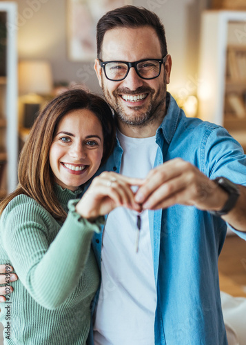 Happy Couple Holding New Home Keys Smiling in Cozy Apartment After House Purchase